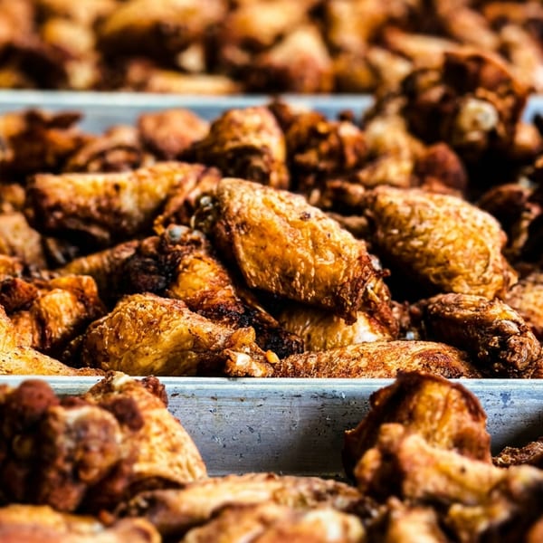 Close-up of a large tray filled with golden-brown, crispy chicken wings, ready to be served.